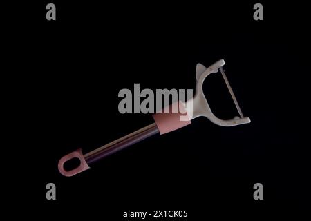 a pink vegetable peeler on a black background Stock Photo
