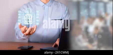 concept information in the cloud. executive in office in front of laptop holding hologram of server surrounded by file folders. Stock Photo