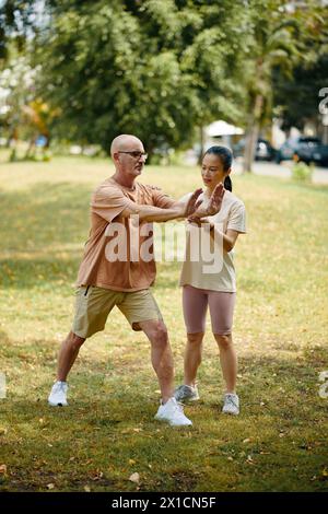 Mature man doing exercises outdoors with personal trainer Stock Photo