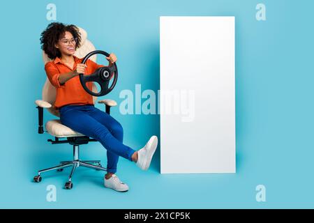 Photo of funny lady worker dressed orange shirt glasses riding auto looking gadget empty space isolated blue color background Stock Photo