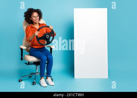 Photo of dreamy lady worker dressed orange shirt glasses riding auto gadget empty space isolated blue color background Stock Photo
