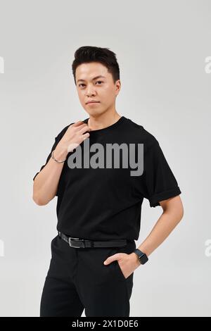 A fashionable young man in a black shirt and pants striking a dynamic pose. Stock Photo