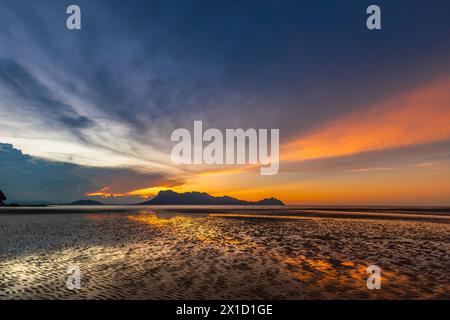 Sunset on the beach in Bako National Park, Borneo, Malaysia, Fiery colors of the sky, low tide of the sea and view of Mount Santubong Stock Photo