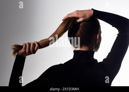 Appealing young elegant woman with long hair tied in a ponytail looks elegant and graceful. Stock Photo