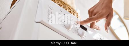 An African American woman pressing button on washing machine. Stock Photo
