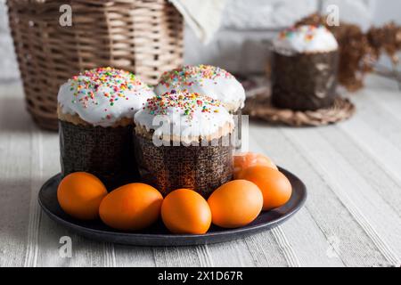 Glaze decorated Easter cakes and yellow colored eggs on a plate on the table. Stock Photo