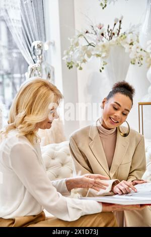 Two sophisticated women engage in a deep conversation while seated on a plush couch in a cozy setting. Stock Photo