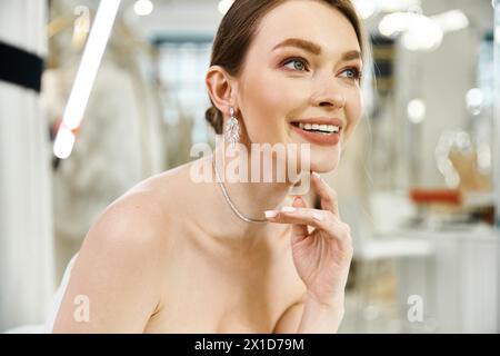 A young, beautiful brunette bride poses elegantly in a white dress in a wedding salon, exuding grace and poise. Stock Photo