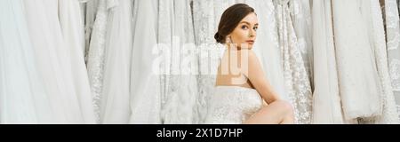 A young brunette bride poses elegantly in a white dress in a wedding salon, exuding charm and grace. Stock Photo
