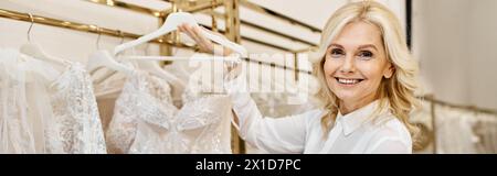 Middle-aged shopping assistant helps customers choose dresses in a wedding salon. Stock Photo