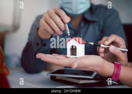 House model on hand over confident team of architects working together in a office. Business, architecture, building construction and real estate conc Stock Photo