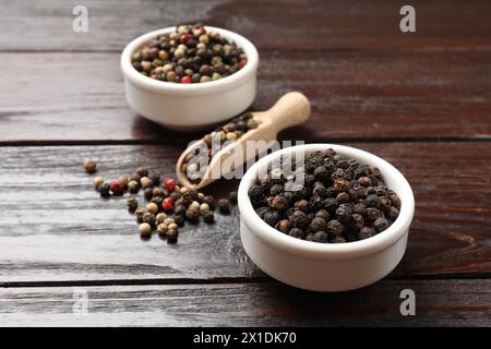 Aromatic spice. Different peppers in bowl and scoop on wooden table Stock Photo