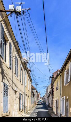 New fiber optic cables for high-speed internet fitted to old metal brackets along narrow town street - Le Blanc, Indre (36), France. Stock Photo