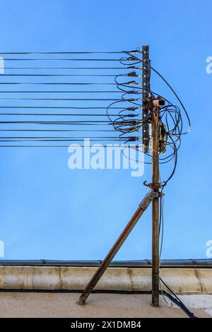New fiber optic cables for high-speed internet fitted to old metal brackets along narrow town street - Le Blanc, Indre (36), France. Stock Photo