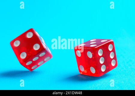 Two red game dices falling on light blue background, closeup Stock Photo