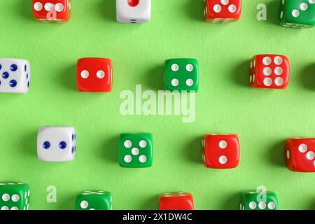 Many color game dices on green background, flat lay Stock Photo