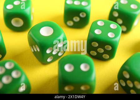 Many green game dices on yellow background, closeup Stock Photo
