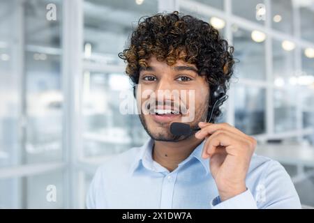 A cheerful customer service representative wearing a headset in a contemporary office environment. His friendly demeanor suggests approachability and professionalism. Stock Photo