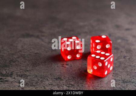 Three red game dices on grey textured table Stock Photo