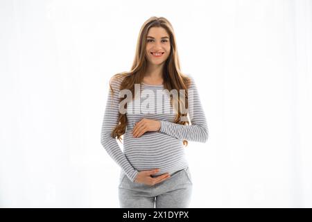 Smiling pregnant woman in casual clothes on white background Stock Photo