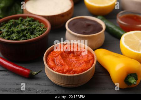 Fresh marinades in bowls and ingredients on grey wooden table, closeup Stock Photo