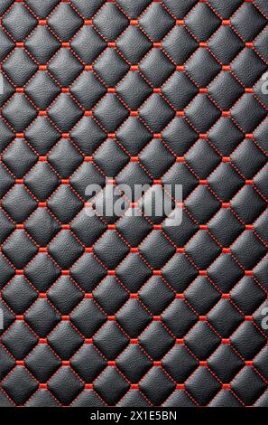 The leather background is made of stitched black leather with even red thread stitching. Vertical image. Stock Photo
