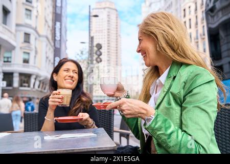 two mature friends having coffee on the terrace of a bar in the city. Stock Photo