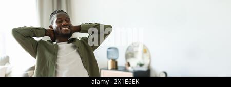 Happy african american man with closed eyes sitting at table Stock Photo