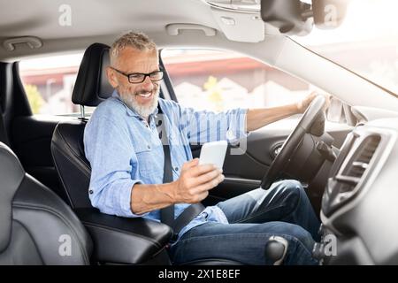 Senior man using a smartphone in the car Stock Photo