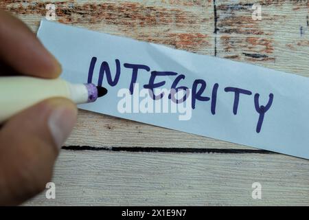 Concept of Integrity write on sticky notes isolated on Wooden Table. Stock Photo