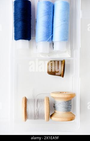 Multicolored skeins of thread in the set. Threads and a thimble in a plastic box. Stock Photo