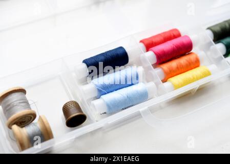 Multicolored skeins of thread in the set. Threads and a thimble in a plastic box. Stock Photo