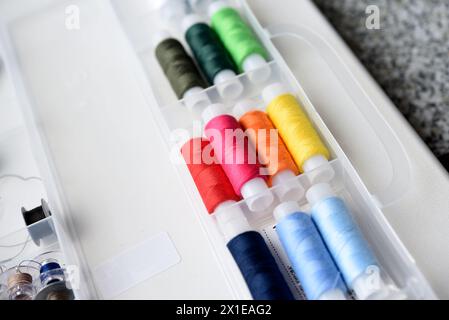 Multicolored skeins of thread in the set. Threads and a thimble in a plastic box. Stock Photo