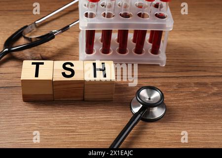 Endocrinology. Stethoscope, cubes with thyroid hormones and blood samples in test tubes on wooden table Stock Photo