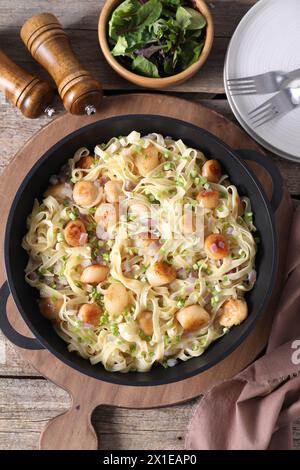 Delicious scallop pasta with onion served on wooden table, flat lay Stock Photo