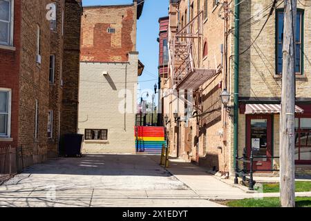 Old storefront and alleyway with staircase painted in rainbow colors.  Woodstock, Illinois, USA. Stock Photo