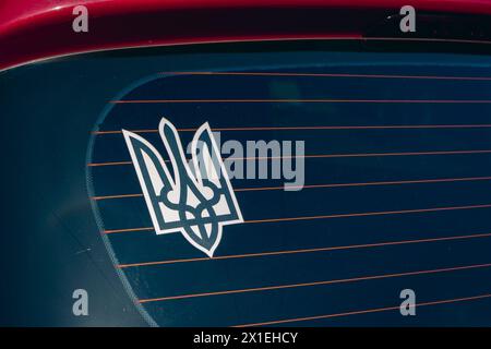 Ukrainian emblem on red car window. Coat of arms of Ukraine. Sticker of Ukrainian national symbol. Patriotic position. Ukrainian official emblem. Stock Photo