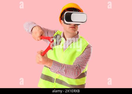 Male worker with pliers using VR glasses on pink background Stock Photo