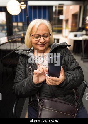 happy blonde senior woman touching cell phone Stock Photo