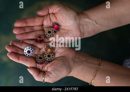 Latin American seamstress hands holding different spools of sewing thread in her palms. Stock Photo