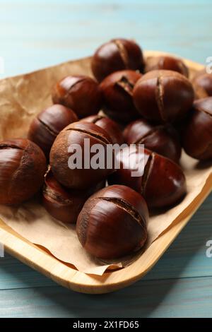 Fresh edible sweet chestnuts in serving plate on light blue wooden table Stock Photo