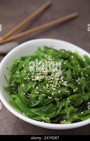 Tasty seaweed salad in bowl served on brown table, closeup Stock Photo