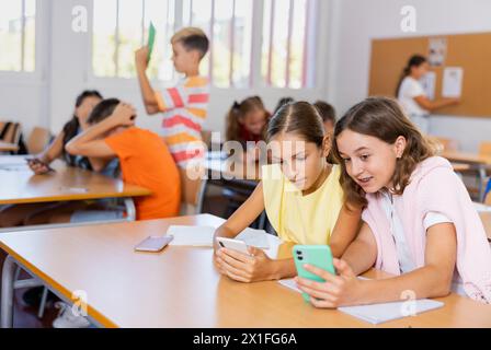 Interested tween students using mobile phones at lesson Stock Photo