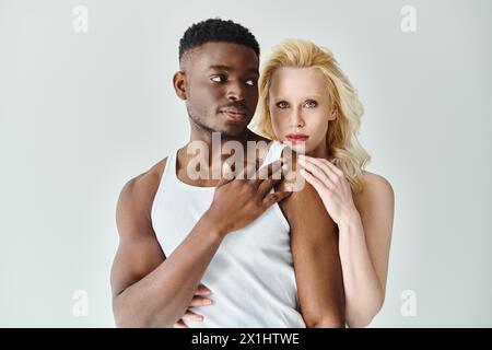 A young multicultural couple joyfully posing for a portrait in a studio against a grey backdrop. Stock Photo