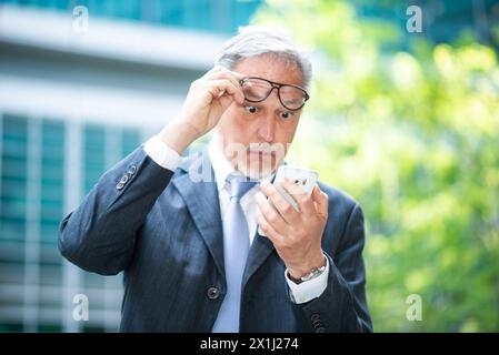 Portrait of an upset senior manager using his smartphone Stock Photo