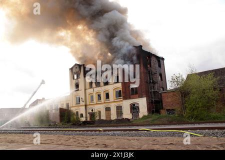 16 April 2024, Mecklenburg-Western Pomerania, Neustadt: Firefighters are working to extinguish a fire in an empty factory building. Following a fire in a vacant factory building in Neustadt-Glewe (Ludwigslust-Parchim district), the railroad line between Ludwigslust and Parchim is still closed. There is a risk that the building could collapse onto the railroad tracks, the federal police announced on Wednesday morning. According to a police spokesperson in Ludwigslust, the affected section is a single-track regional line. The Ostdeutsche Eisenbahn (ODEG) operates the regional train RB14 on the l Stock Photo