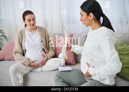 Two women, one pregnant, engage in a deep discussion while seated on a cozy couch during a prenatal course. Stock Photo