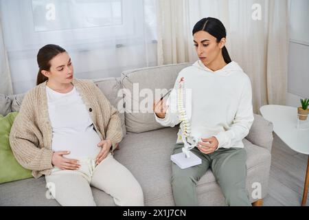 Two pregnant women engage in a friendly conversation while seated on a couch during a parents course. Stock Photo