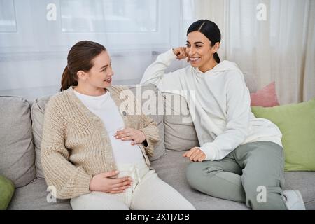 Two women, a pregnant woman and her trainer, engage in a meaningful conversation on a couch during parents courses. Stock Photo