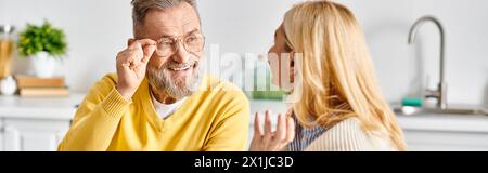 A mature loving couple in cozy homewear gaze fondly at each other in the kitchen of their home. Stock Photo